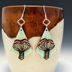 "These one of a kind earrings feature detailed paintings of mushrooms working from my own photo of mushrooms I found on a hike. These light, wood earrings are hand-painted with acrylic paint and liquid pearlescent acrylic inks, then sealed with liquid glass. The edges of the earrings are painted with gold paint. I hand formed the earring hooks and jump rings from 20 gauge half hard sterling silver wire.  Earrings (painted wood) each approximately 1 & 5/8\" long, 1 & 1/8\" in widest part Earrings with attached earring wires each approximately 2.75\" long **Listing is for earrings only and does not include any props or pottery as seen in the photos. Your earrings will arrive ready for gifting in a gift box inside the package." Nickel-free Mushroom-shaped Earrings For Gifts, Nickel-free Mushroom Shaped Earrings As Gift, Unique Mushroom Design Earrings For Gift, Unique Mushroom Design Earrings As Gift, Whimsical Mushroom Print Jewelry Gift, Mushroom Earrings, Detailed Paintings, Earring Wires, Made Jewelry