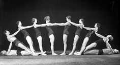 a group of people standing around each other in front of a black and white photo