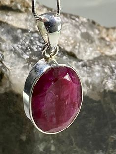 An exquisite Raw Red Ruby and silver pendant. The stone is a good size, of a beautifully deep vivid ruby red, oval-cut and set in the classic bezel.  The pendant measures - 2.1cm Long x 1.5cm wide x 0.6cm deep. Weight - 6 grams. This pendant is made utilising hypoallergenic pure 925 silver that is nickel, lead and cadmium free. Customer can choose to purchase the pendant in the following options: 1 - The pendant separately.  2 - The pendant Including the stunning solid Italian silver 1mm diamete Classic Ruby Round Pendant Jewelry, Classic Round Ruby Pendant Jewelry, Faceted Oval Ruby Jewelry, Classic Red Oval Pendant Jewelry, Oval Faceted Ruby Jewelry, Oval Ruby Jewelry With Faceted Detail, Red Faceted Oval Jewelry, Red Oval Faceted Jewelry, Faceted Oval Red Jewelry