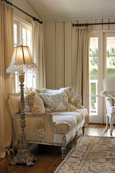 a living room filled with furniture next to a window covered in curtains and drapes