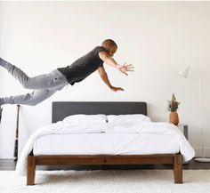 a man jumping in the air over a bed