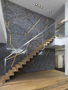 a modern staircase with stone wall and metal handrails in an empty room that has wood flooring