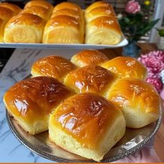 bread rolls are sitting on a platter in front of other trays with flowers