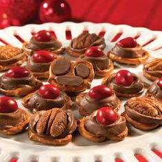 a white plate topped with cupcakes covered in chocolate frosting and cherries