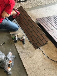 a man sitting on the ground working on a piece of wood that is being worked on