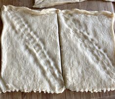 four uncooked pizza doughs sitting on top of a wooden cutting board