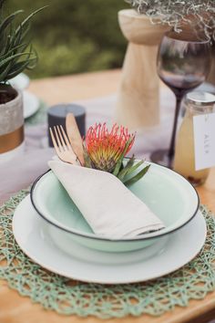 a table set with plates, silverware and succulents