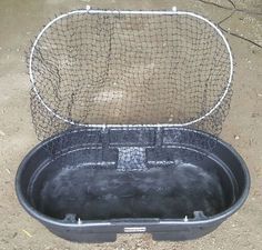 a large metal bucket with a net on the top and bottom, sitting in dirt