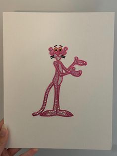 a hand holding up a piece of paper with a pink cat on it's face