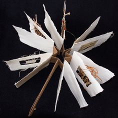 an origami flower made out of paper on a black surface with brown and white strips