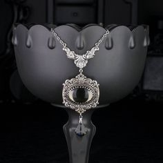 "💀 DESCRIPTION: This y necklace features a large vintage oval cabochon, in Black Diamond, that was hand set into a crown edge setting and layered onto ornate stampings with floral and flourish details. A faceted crystal pendant from Swarovski® dangles from the bottom. The entire ensemble dangles from beautiful Rococo style connector. The cable chain was finished with a lobster clasp and an extender. 💀 SIZE & MATERIALS: The vintage glass cabochon was made from glass in the 1970's and is from We Vintage Oval Cabochon For Jewelry Making, Silver Cameo Jewelry For Party, Party Silver Cameo Jewelry, Vintage Handmade Oval Cabochon Necklaces, Gothic Oval Collectible Jewelry, Vintage Handmade Necklaces With Oval Cabochon, Vintage Handmade Oval Cabochon Necklace, Collectible Gothic Oval Jewelry, Gothic Silver Oval Necklace