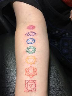 a person with a tattoo on their arm that has seven chakras in different colors