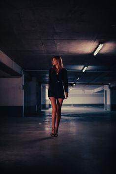 a woman is walking in an empty parking garage with no one on her feet or shoes