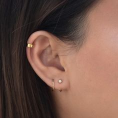 a close up of a woman's ear with two small gold hoops on it