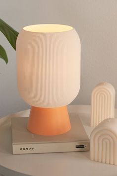 a white and orange lamp sitting on top of a table next to a remote control