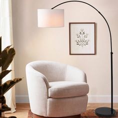 a living room with a white chair and a black lamp on the floor next to it