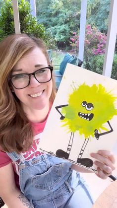 a woman holding up a drawing of a monster