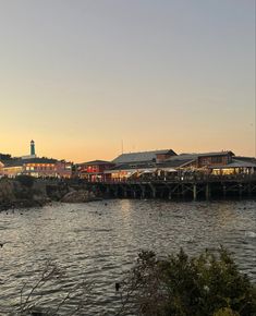 a body of water with buildings on the other side and a lighthouse in the distance