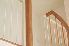 an image of a stair case with wood handrails and white painted walls in the background