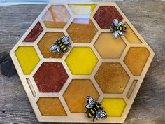 three bees sitting on top of a piece of honeycomb with red, yellow and brown colors