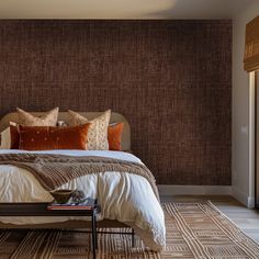 a bed with pillows and blankets on top of it next to a window in a bedroom