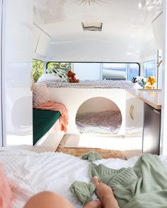 a woman laying on top of a bed next to a dog house in the back of a van