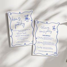 two wedding cards with blue ink on them next to a plant and white sheet of paper