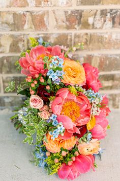 a bouquet of flowers sitting on top of a white table next to a brick wall