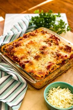 a casserole dish with cheese and meat in it on a table next to two bowls