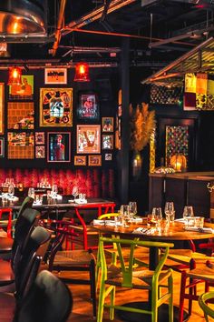 the interior of a restaurant with colorful tables, chairs and pictures on the wall behind them