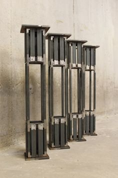 four metal structures sitting in front of a wall with no one on it's side