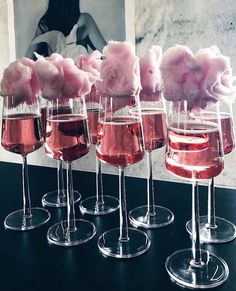 five wine glasses filled with pink liquid and cotton floss in front of a photo