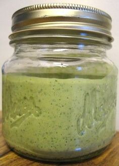 a jar filled with green liquid sitting on top of a wooden table