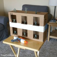 a cardboard house with toy soldiers on the front and sides, sitting on top of a small table