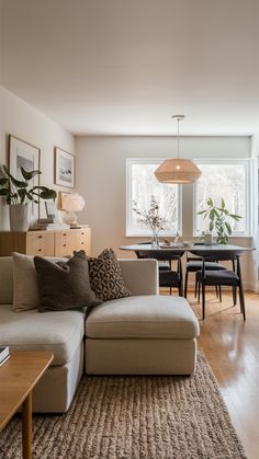 a living room filled with furniture next to a dining room table and chairs on top of a hard wood floor