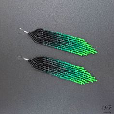 pair of green and black beaded earrings on grey background