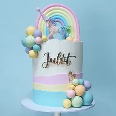 a birthday cake decorated with rainbows, balloons and a unicorn on top that says just