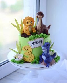 there is a cake decorated with animals and plants on the table next to a window