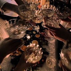 several people clinking wine glasses on top of a table covered in confetti