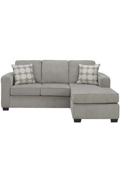 a gray sectional couch with pillows on it and a footstool next to it