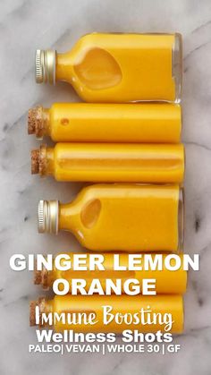 three bottles filled with orange juice sitting on top of a marble counter next to each other