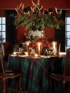 the table is set with candles and christmas decorations on it, along with deer antlers