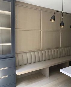 an empty bench in a room with two lights on the wall and cabinets behind it