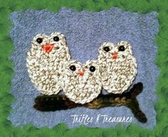 three crocheted birds sitting on top of a tree branch in front of a blue background