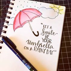 a notebook with an umbrella drawn on it next to a pen and paper that says let a smile be your umbrella on rainy day