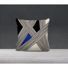 a black and white pillow with blue triangle on the front, sitting on a table