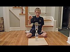 a young boy sitting on the floor with a bottle of water in front of him