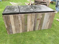 an old wooden box sitting on top of green grass next to other wood boxes and pallets