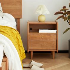 a bedroom with a bed, nightstand and plant on the side table next to it