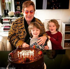 a man and two children are sitting in front of a cake with candles on it